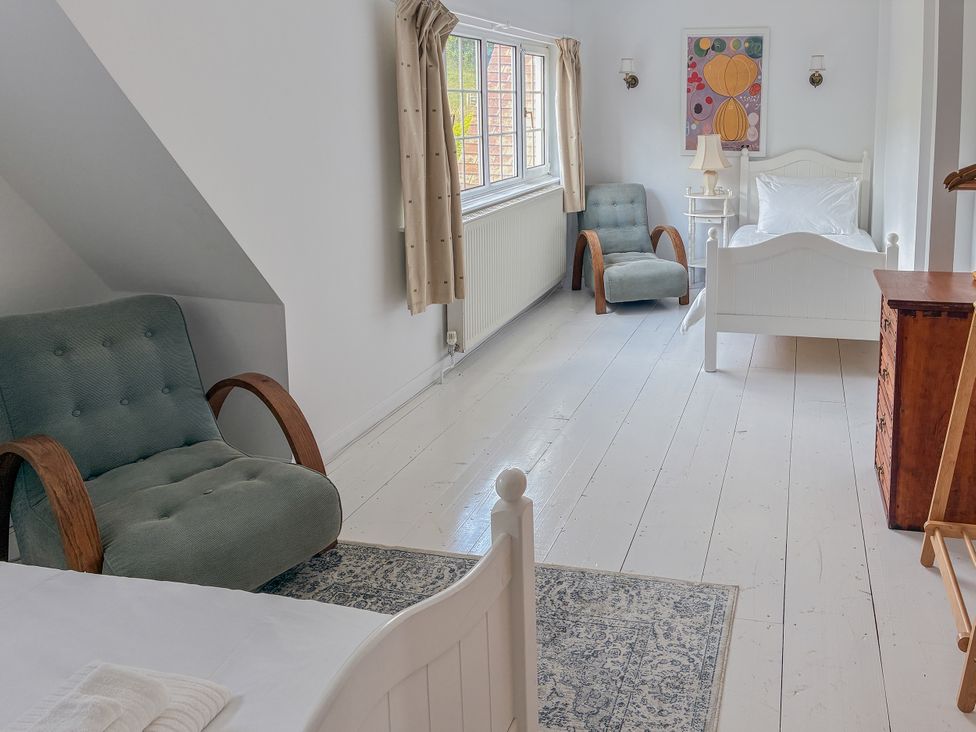 A bedroom with a bed, armchairs, and a table at Tuckers Farm in Gatcombe