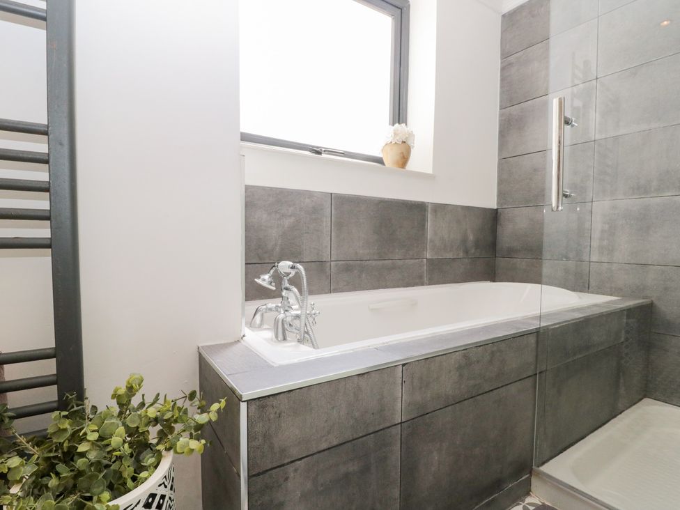 A bathroom with a bathtub and shower at Sea Haven Hunmanby Gap near Primrose Valley