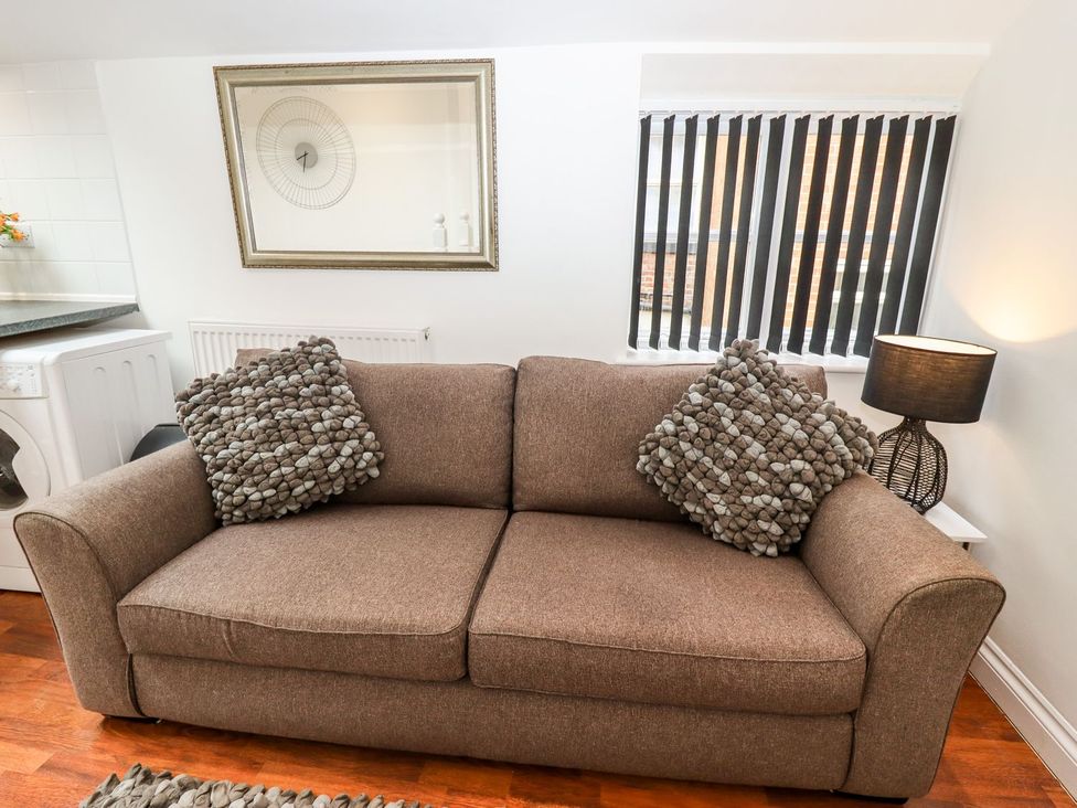 A living room with a brown sofa and a mirror at Bobby's in Whitby