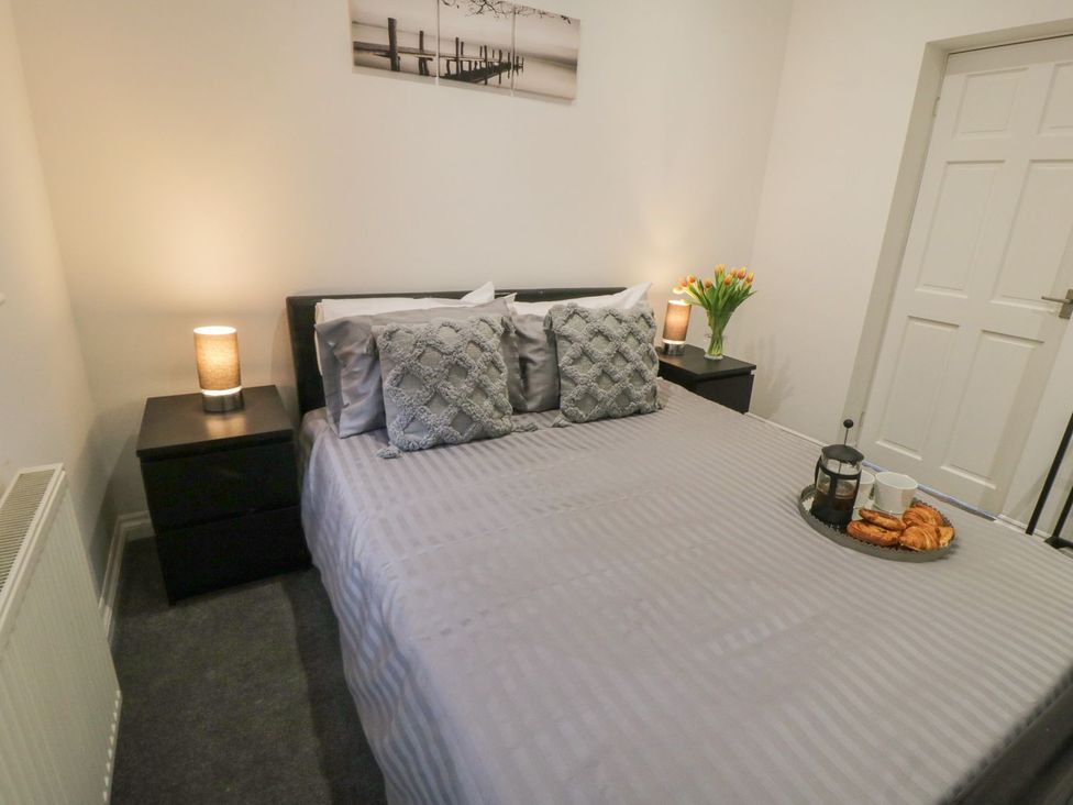 A bedroom with a bed, nightstand and flowers at Ted's Place in Whitby