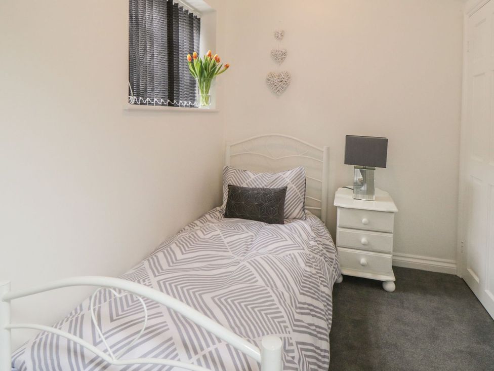 A bedroom with a single bed, nightstand, and lamp at Ted's Place in Whitby