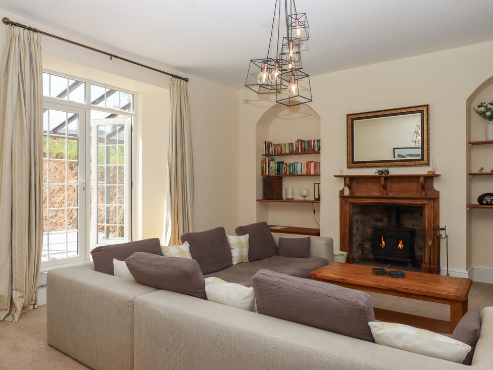A living room with a sofa, bookshelf, fireplace and lighting at Littleham Court Manor in Littleham near Bideford