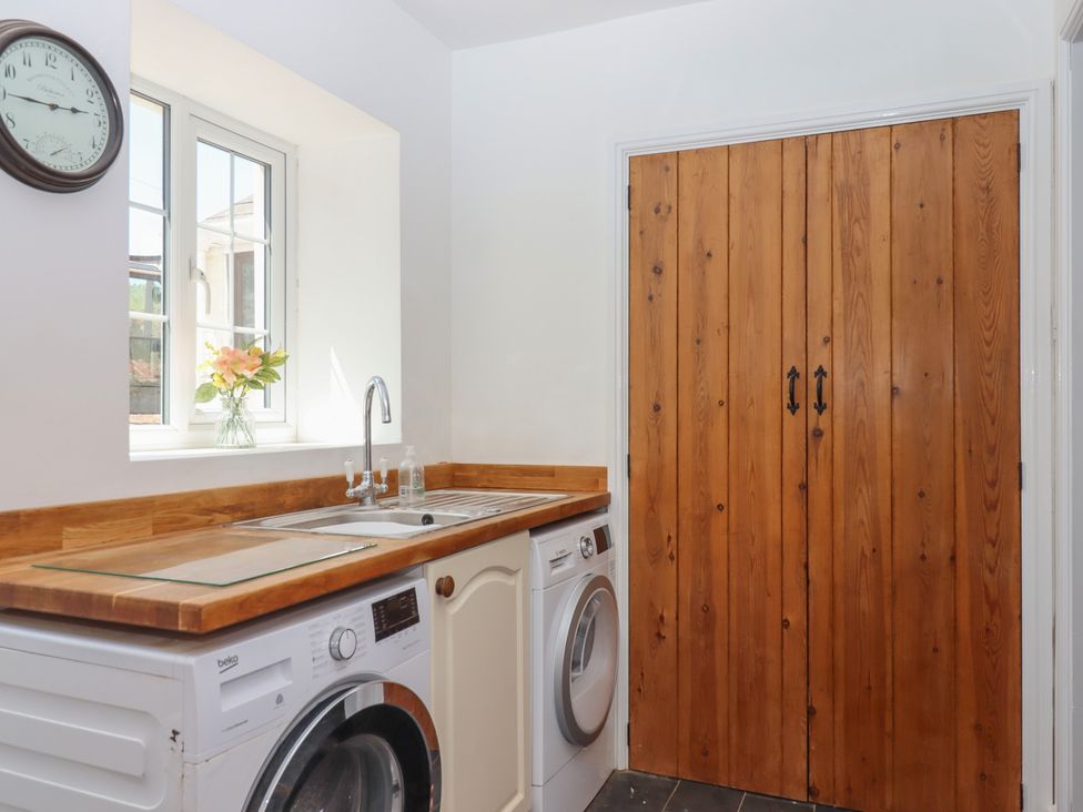 A laundry room featuring a washing machine, sink, and wooden door at Littleham Court Manor in Littleham near Bideford