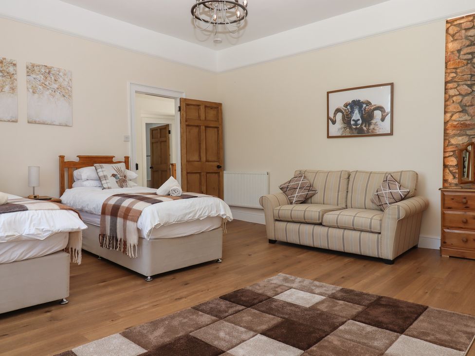 A bedroom with two beds and a sofa at Littleham Court Manor near Bideford
