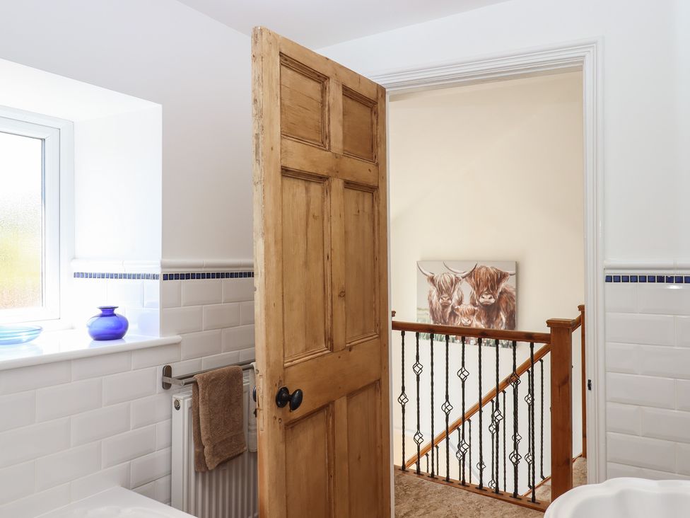 A bathroom with a wooden door and window at Littleham Court Manor in Littleham near Bideford