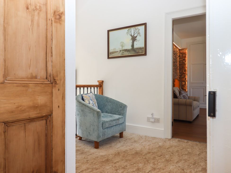 A hallway with an armchair and a painting at Littleham Court Manor in Littleham near Bideford