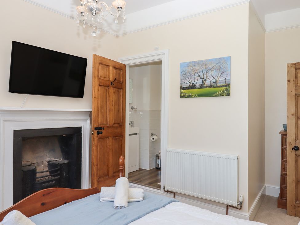 A bedroom with a television mounted on the wall and a door leading to a bathroom at Littleham Court Manor Littleham near Bideford
