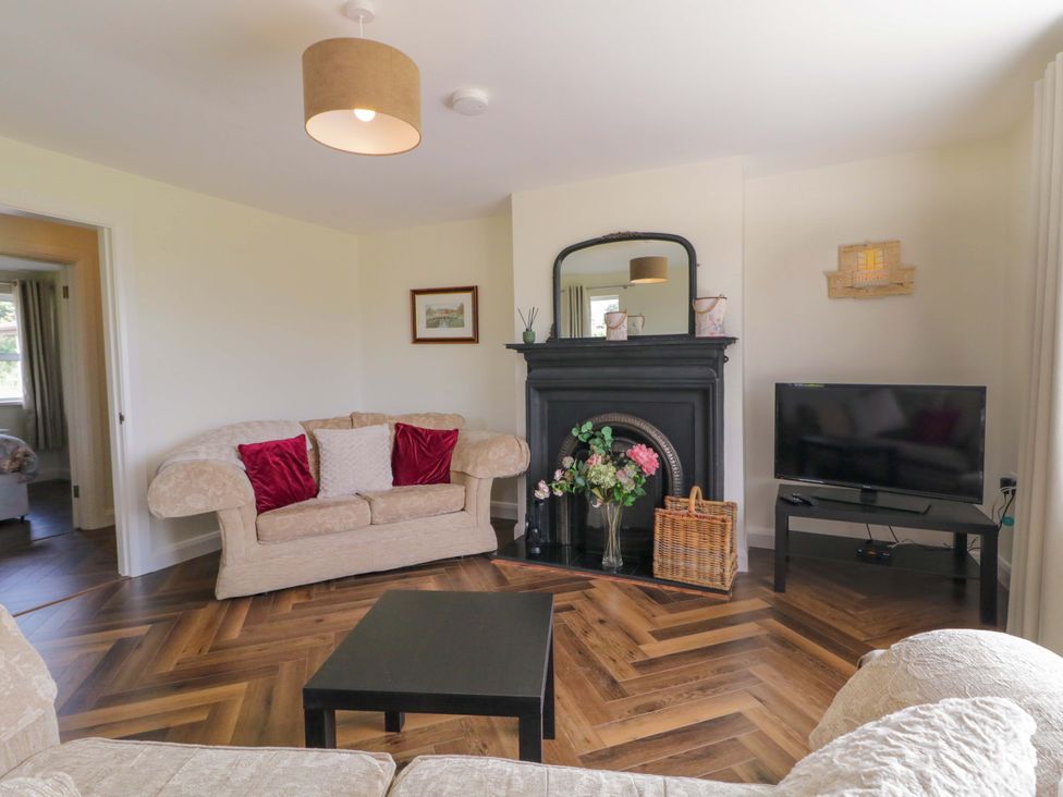 A living room with a sofa, fireplace, and television at Ard Na Mara