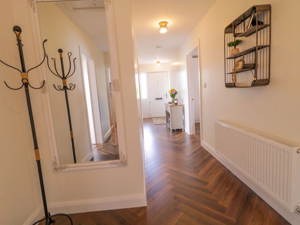 A hallway with a coat rack, mirror, and shelf at Ard Na Mara
