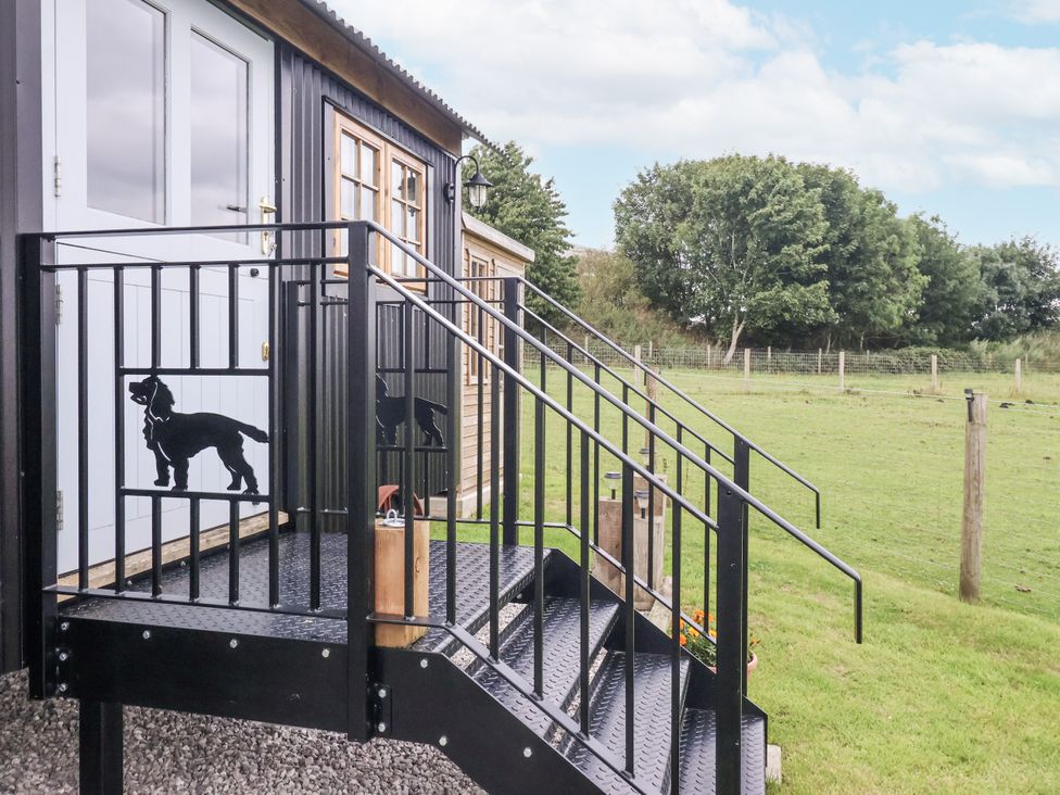 A staircase with a handrail leading to a door at Shepherd's Hut in Market Weighton