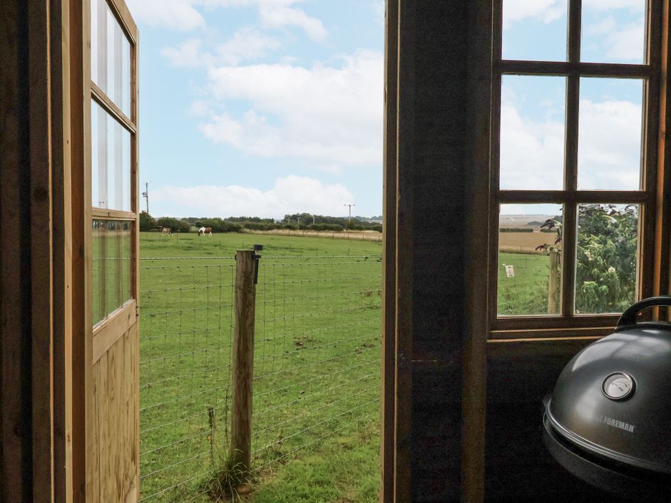 A view of an outdoor field from inside a hut at Shepherd's Hut in Market Weighton
