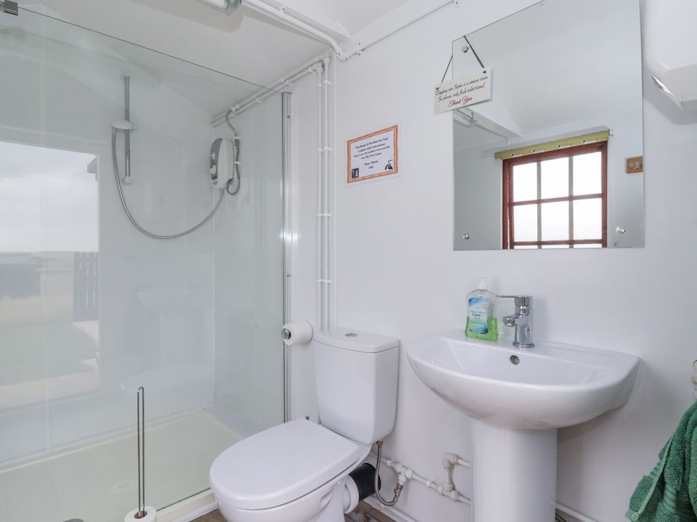 A bathroom with a shower, toilet, and sink at Shepherd's Hut in Market Weighton