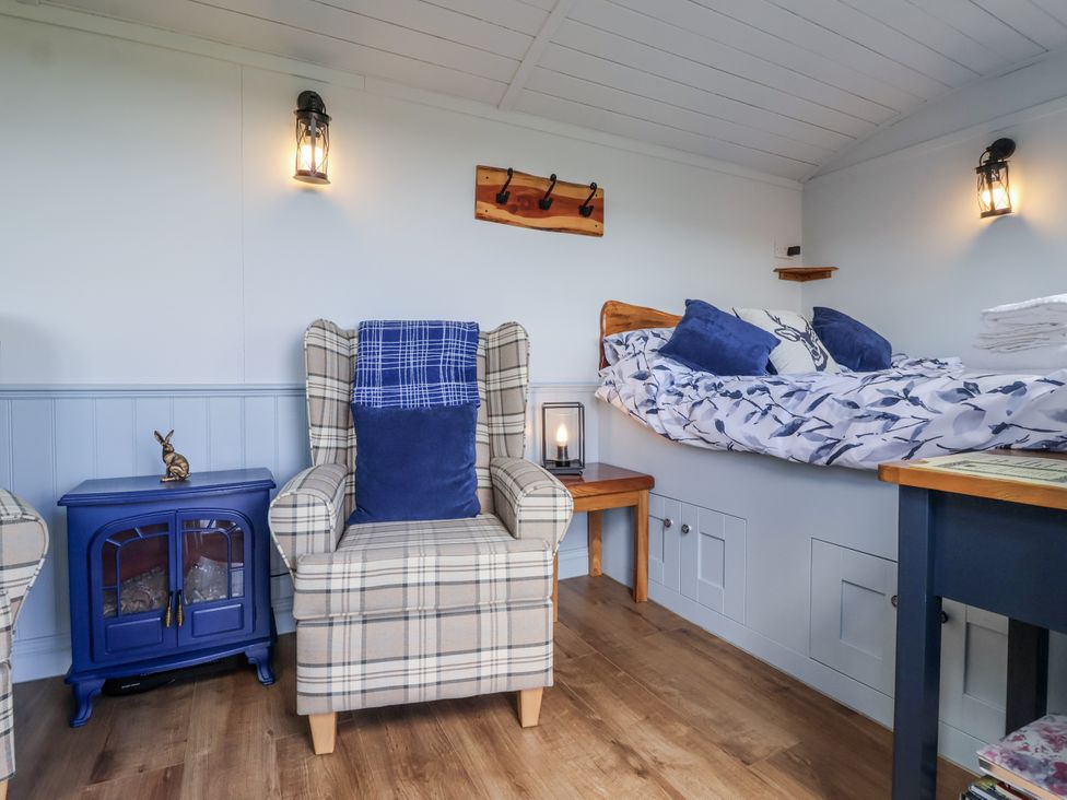A bedroom with armchair and bed at Wolds Hoot in Market Weighton
