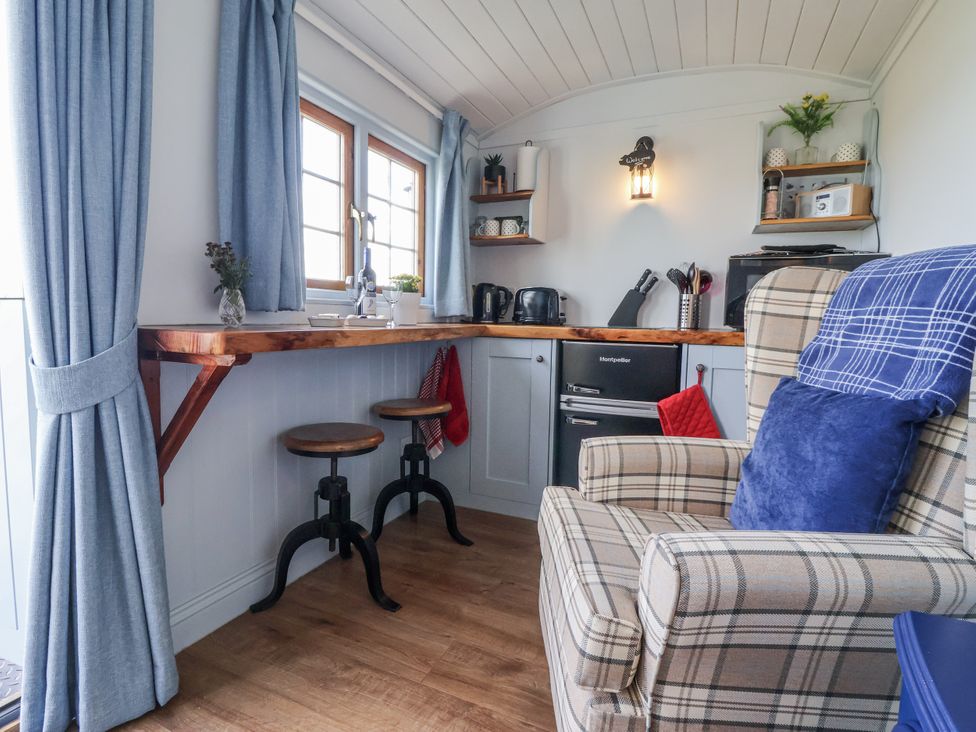 A kitchen with stools and a refrigerator at Wolds Hoot in Market Weighton