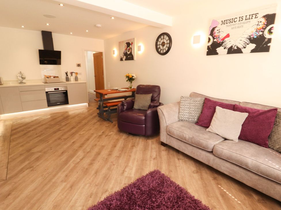 A living room with kitchen area and dining table at Flat 1 in Carnforth