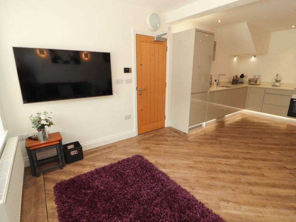 A kitchen with a TV and door at Flat 1 in Carnforth