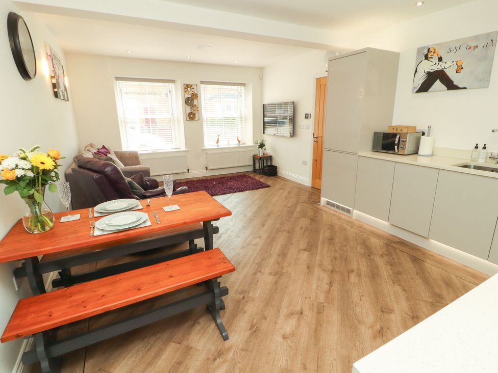A living room and kitchen area with a dining table and sofa at Flat 1 Carnforth