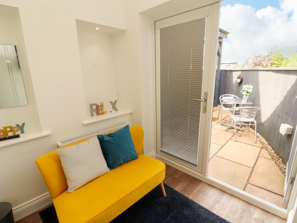 A living room with a yellow sofa and access to a patio at Flat 1 in Carnforth