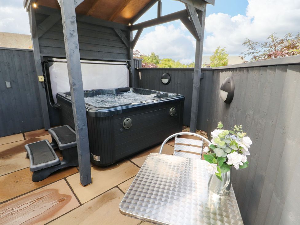 An outdoor area with a hot tub and table at Flat 1 Carnforth