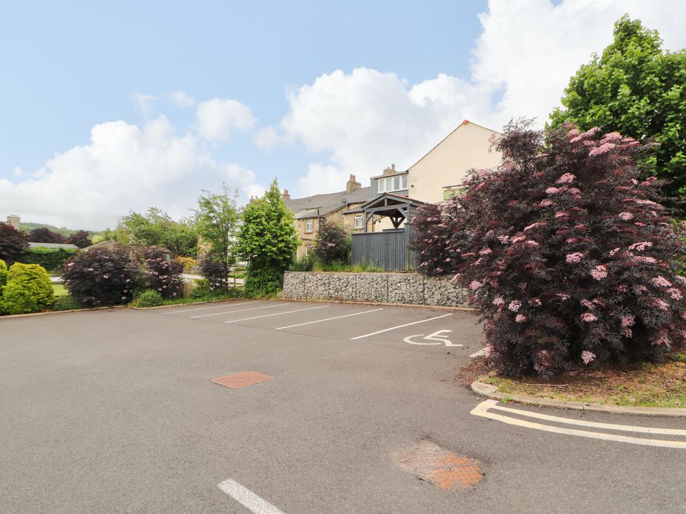 A parking lot with trees and flowers next to a building at Flat 1 Carnforth