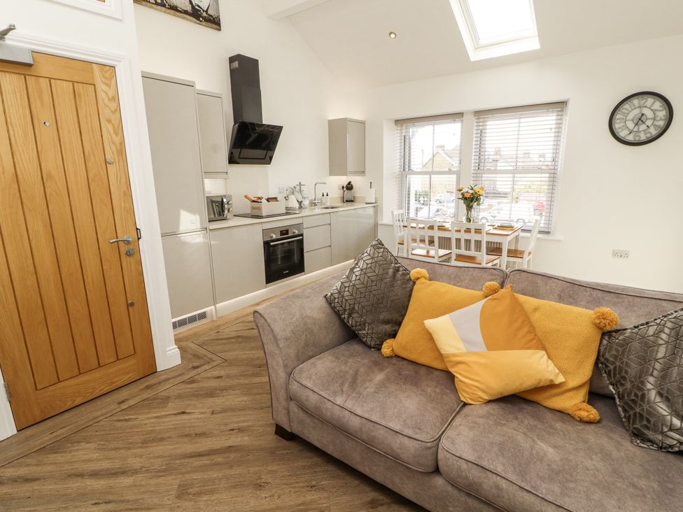 A living room with a sofa and kitchen area at Flat 2 in Carnforth