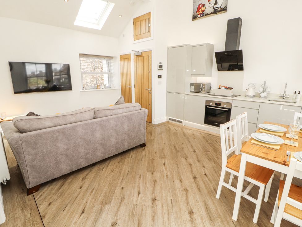 A living room with a sofa a kitchen unit and a dining table at Flat 2 Carnforth