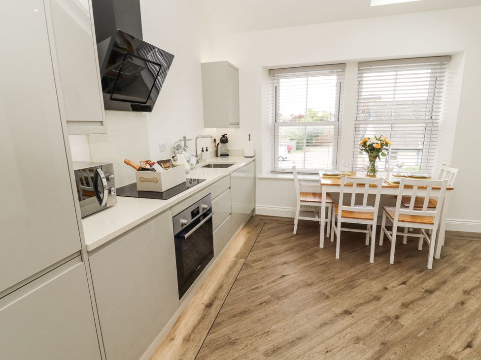 A kitchen with cabinets and dining table at Flat 2 in Carnforth