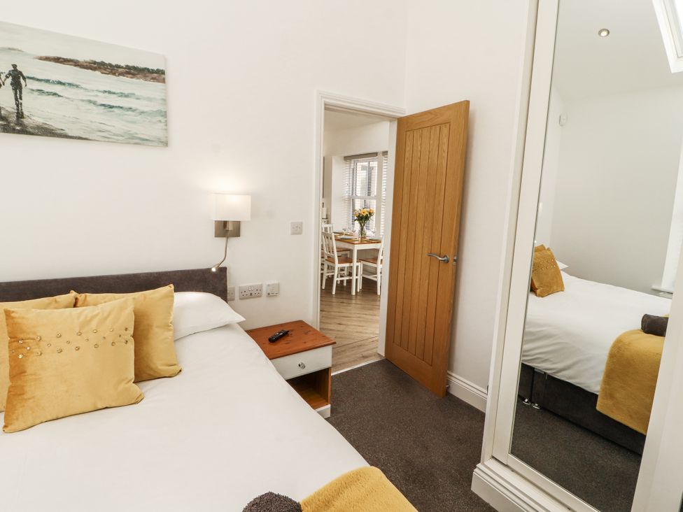 A bedroom with a bed and doorway to dining area at Flat 2 in Carnforth