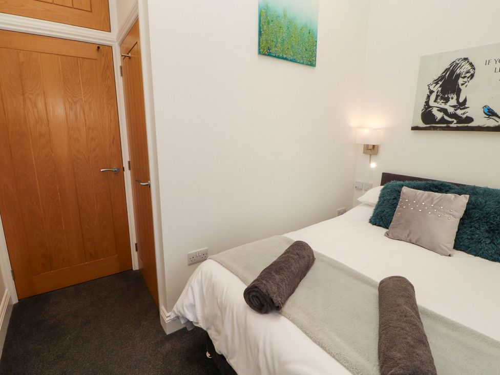 A bedroom with a bed, towels, and wall art at Flat 3 in Carnforth