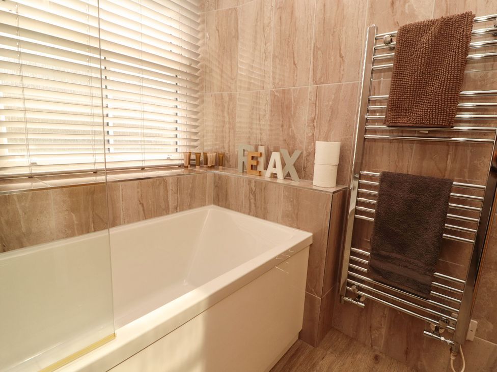 A bathroom with a bathtub and towel rack at Flat 3 in Carnforth