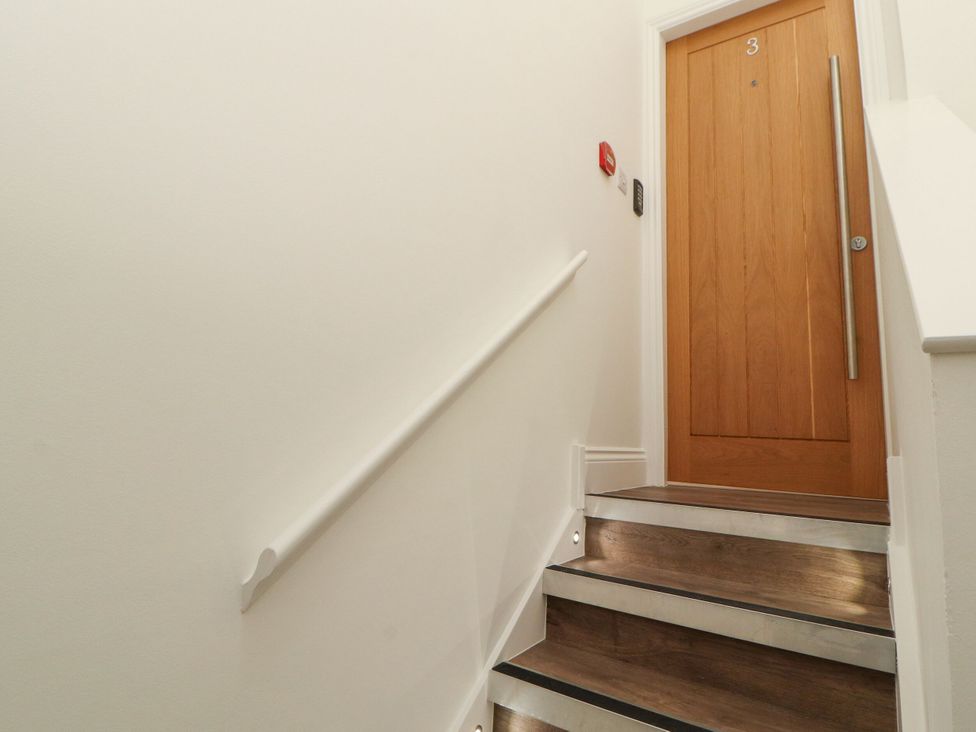 A staircase with wooden stairs and a door at Flat 3 in Carnforth