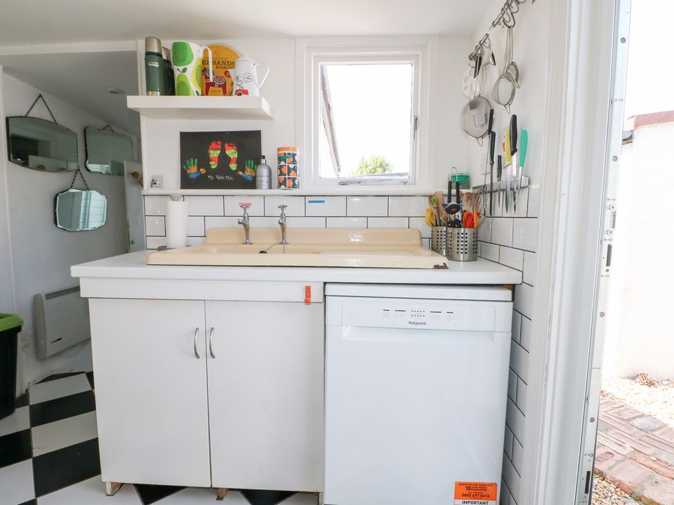 A kitchen with sink, dishwasher, and utensils at Harbour Road Quirky Beach Railway Carriages, Pagham