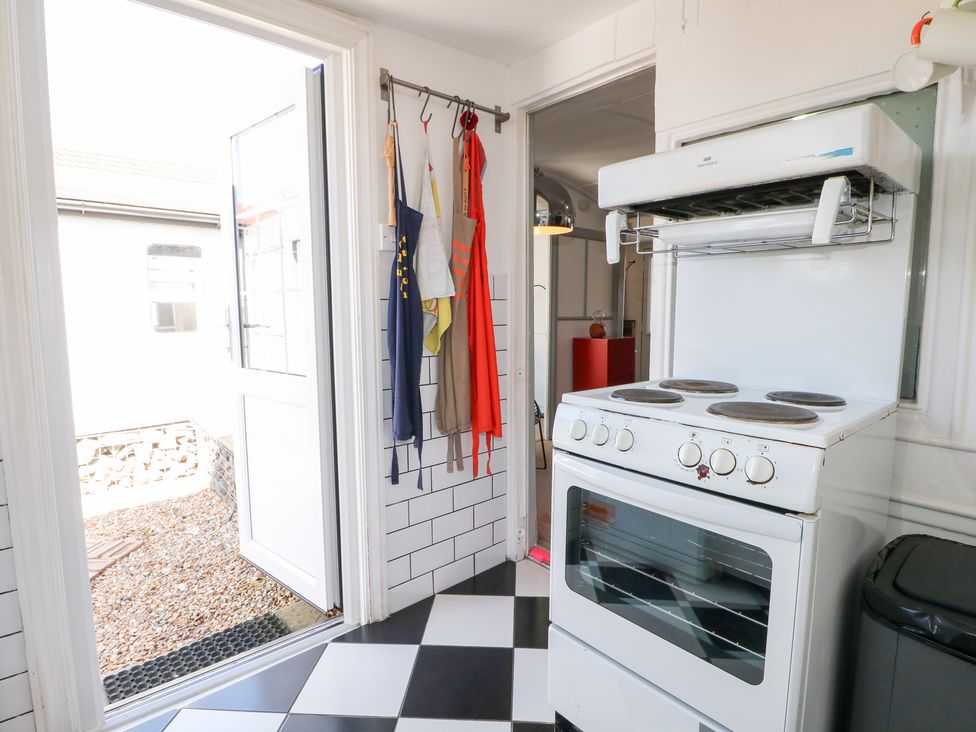 A kitchen with a stove and aprons hanging at Harbour Road Quirky Beach Railway Carriages Pagham