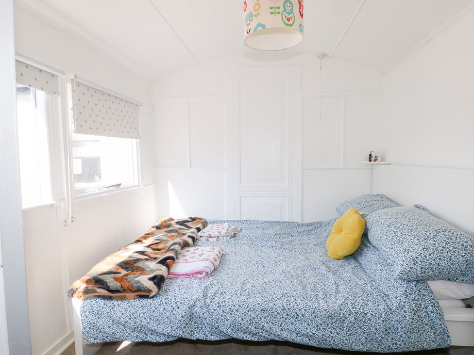 A bedroom with a bed and blanket at Harbour Road Quirky Beach Railway Carriages in Pagham