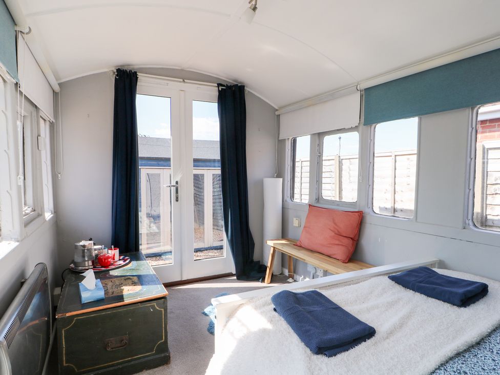 A bedroom with a bed and table at Harbour Road Quirky Beach Railway Carriages, Pagham