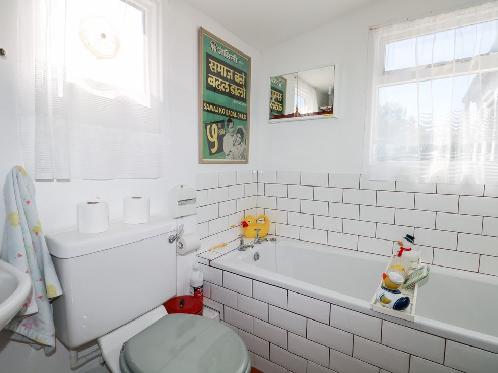 A bathroom with a toilet, bath tub, and sink at Harbour Road Quirky Beach Railway Carriages Pagham