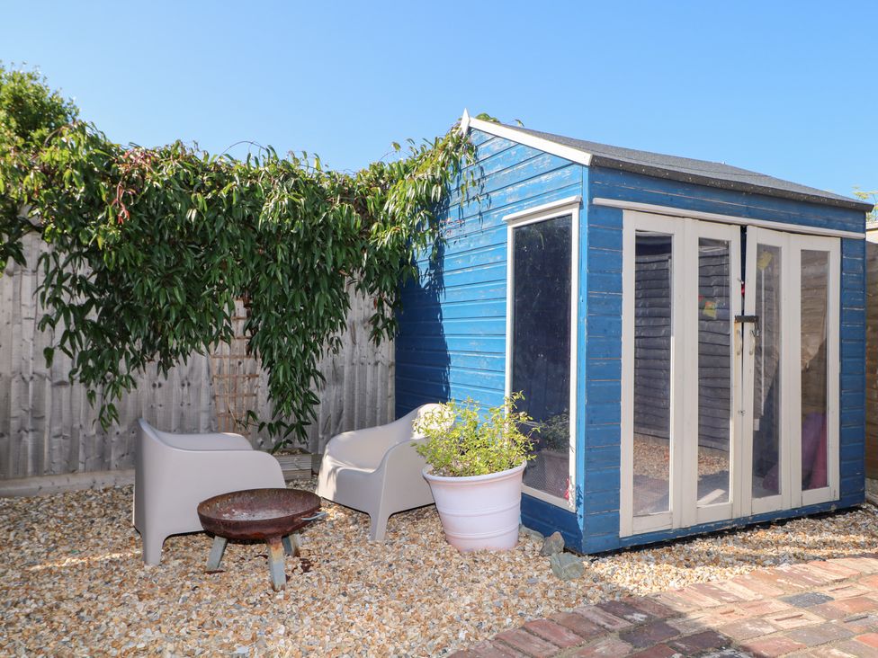 A garden with a blue shed and white chairs at Harbour Road Quirky Beach Railway Carriages Pagham