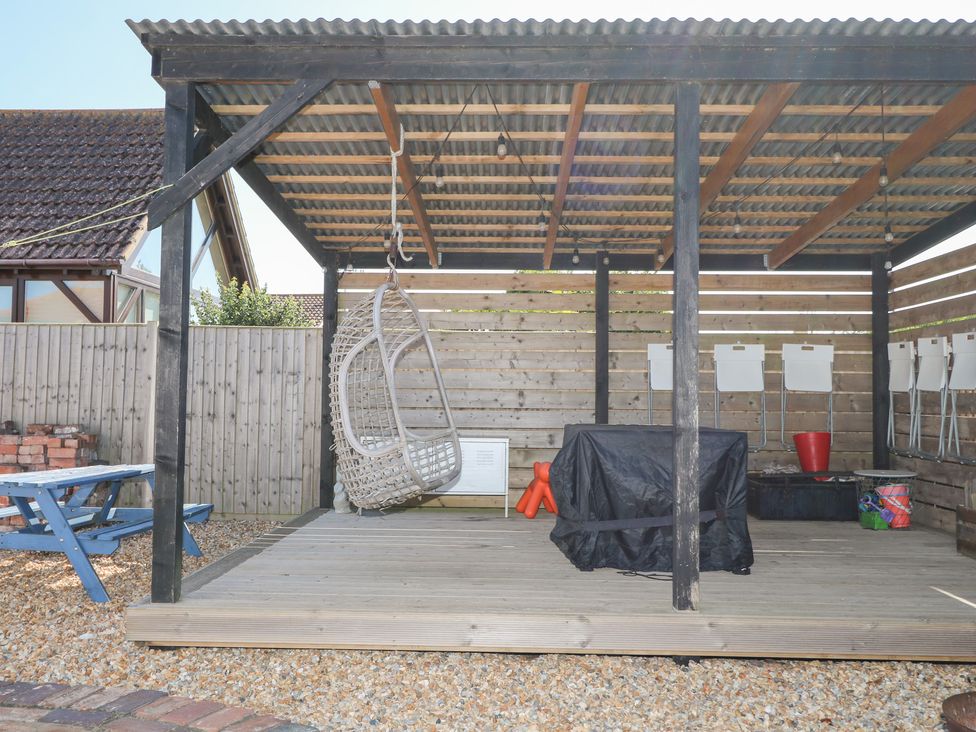 An outdoor shelter with a hanging chair and table at Harbour Road Quirky Beach Railway Carriages, Pagham