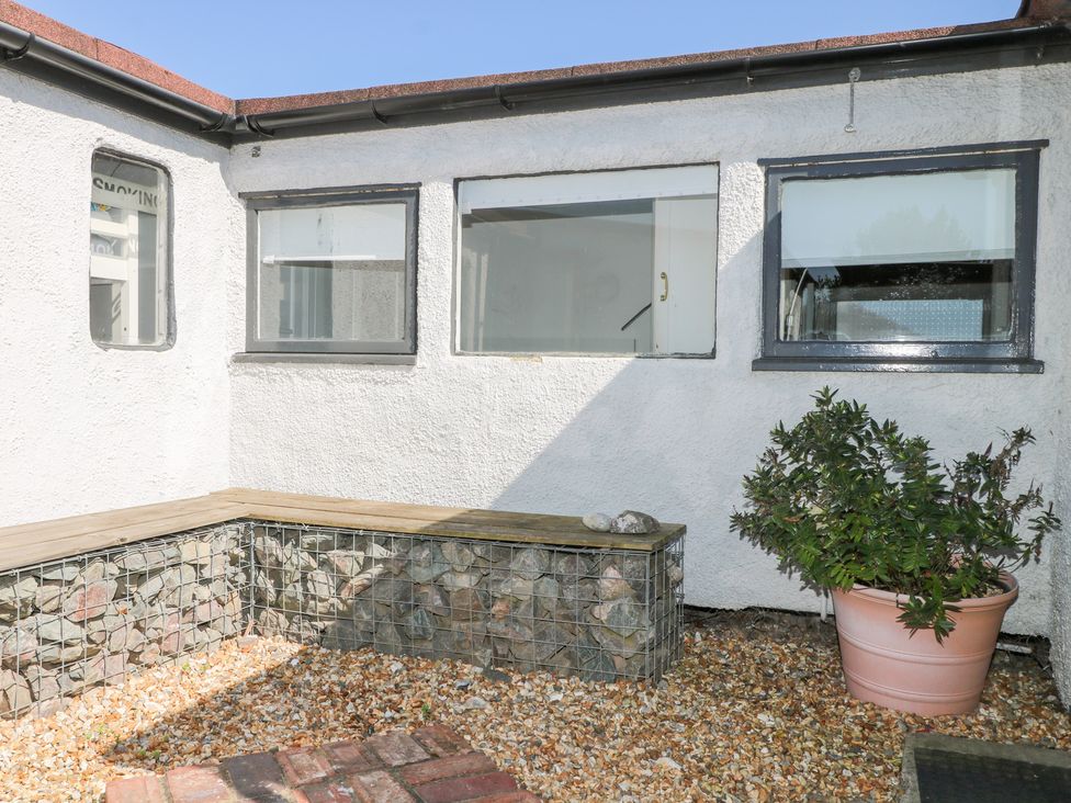 A garden with a stone wall and a plant at Harbour Road Quirky Beach Railway Carriages in Pagham