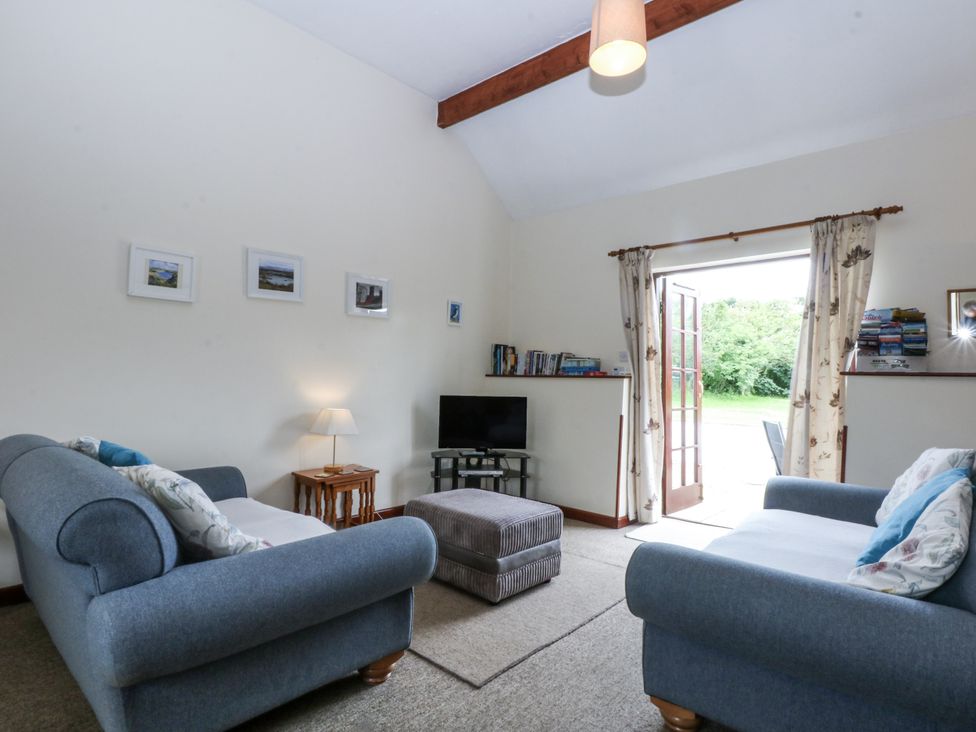 A living room with sofas and a television at Florence Cottage in Holyhead