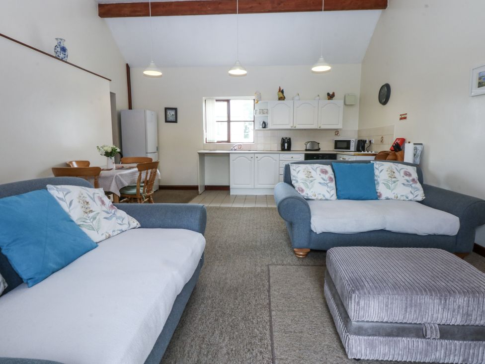 A living room with a sofa and kitchen area at Florence Cottage in Holyhead