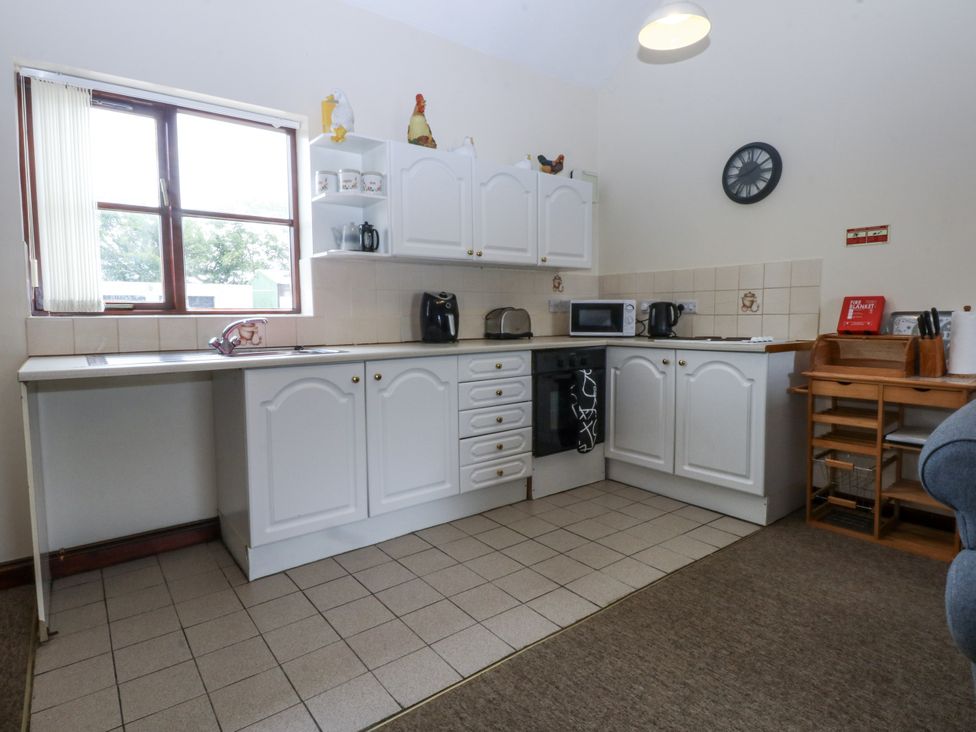 A kitchen with cabinets, sink, and appliances at Florence Cottage in Holyhead