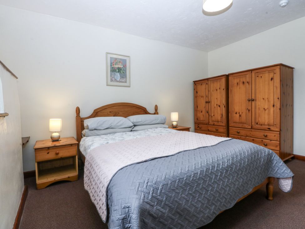 A bedroom with a bed, bedside table and wardrobe at Florence Cottage in Holyhead