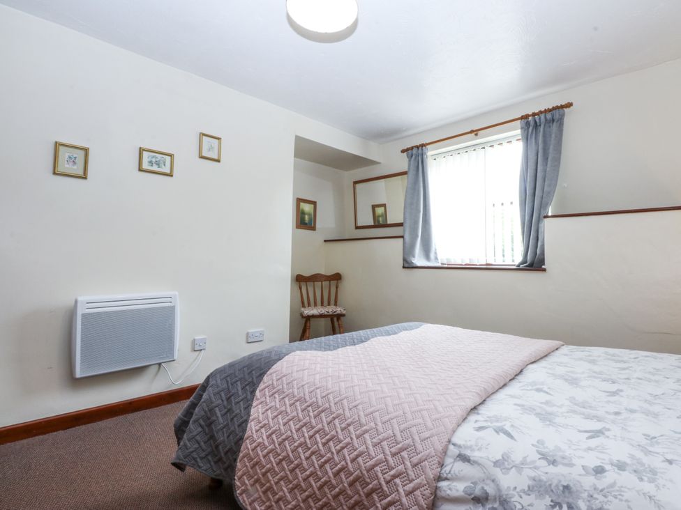 A bedroom with a bed and chair at Florence Cottage in Holyhead