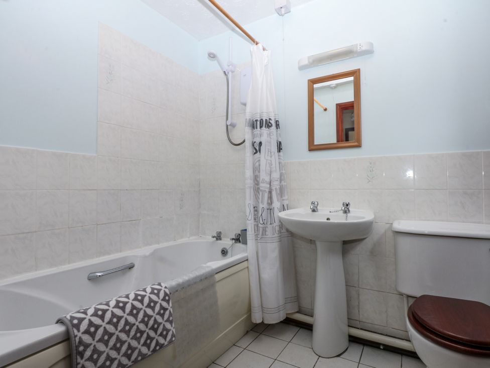 A bathroom with a bathtub, shower, wash basin, and toilet at Florence Cottage Holyhead