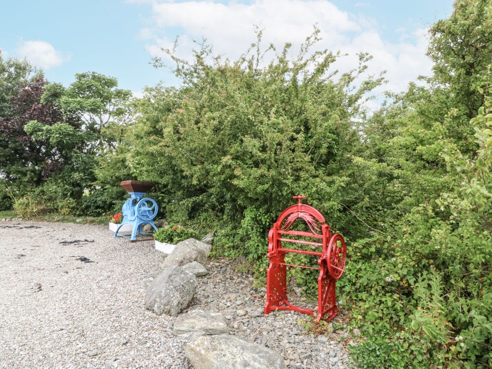 An outdoor area with blue and red machines among greenery at Florence Cottage in Holyhead