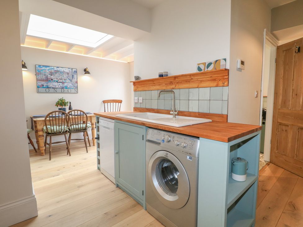 A kitchen with a washing machine and a dining table at Lower Floor Flat