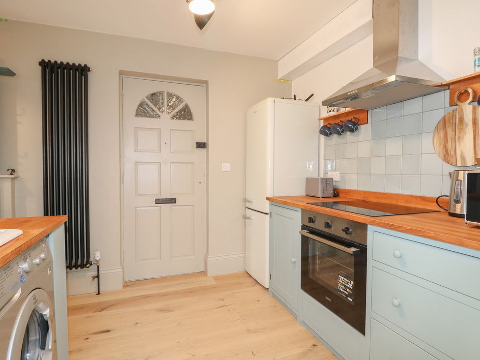 A kitchen with appliances and a door at Lower Floor Flat