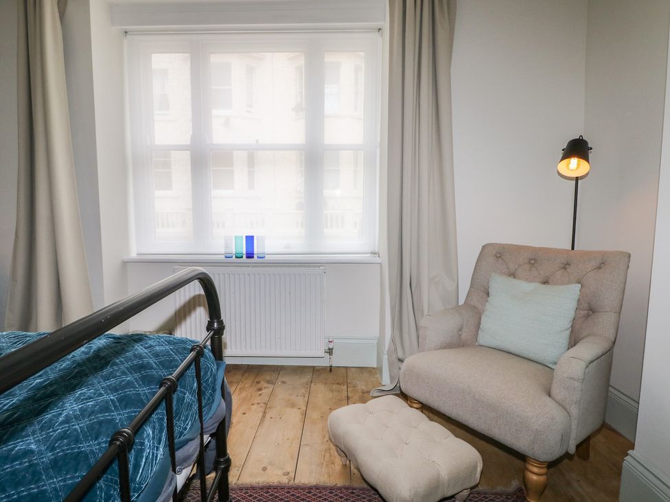 A bedroom with a bed and an armchair at Lower Floor Flat