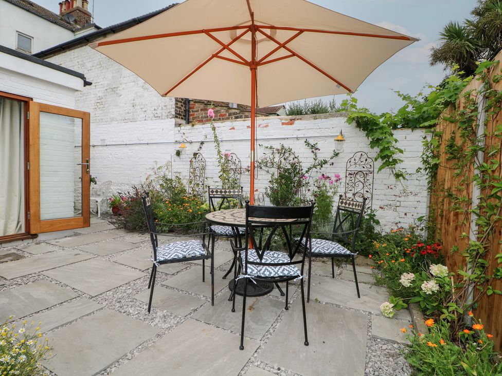 A garden with a table and chairs under an umbrella at Lower Floor Flat in 